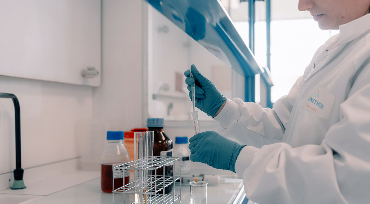 A female scientist in a lab coat is holding a test tube, representing her role in conducting experiments and research.